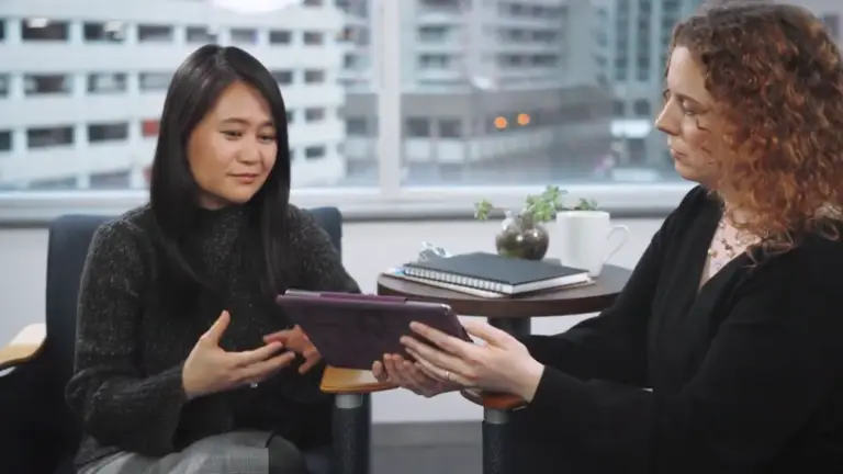 Two women in an office discussing a tablet